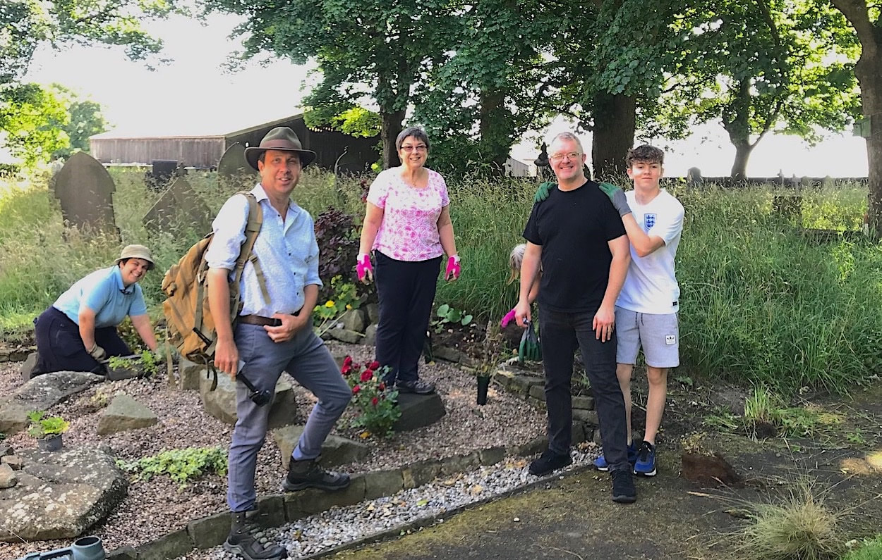 A visitor ad tidy-up helpers in Farnley Tyas churchyard